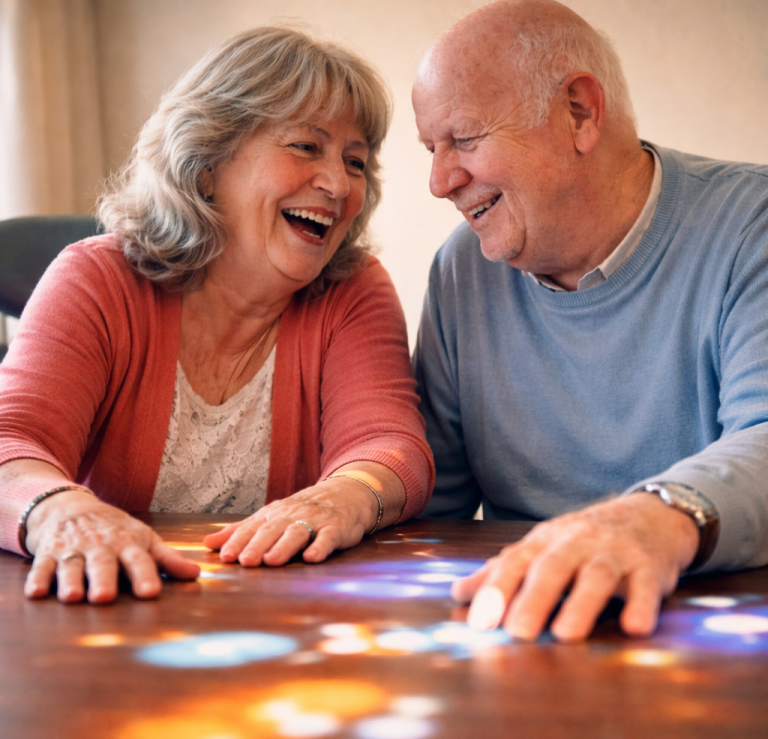 Aktionswoche Tovertafel Sachsen Ein älteres Paar lächelt sich an einem Tisch an und hält Händchen.